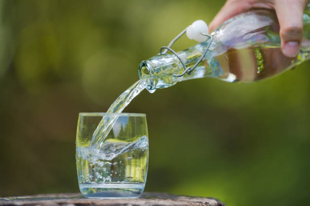 istock Hand pouring drink water from bottle into glass 1165253370
