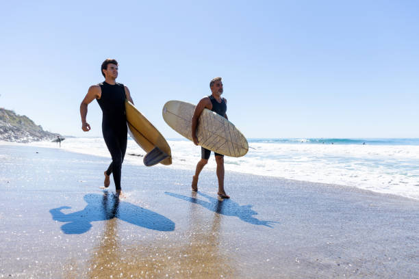 istock Father and son surf on the beach in California 1165255643