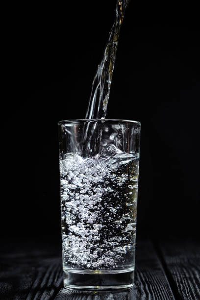istock water pours into a glass on a black background 1165255886