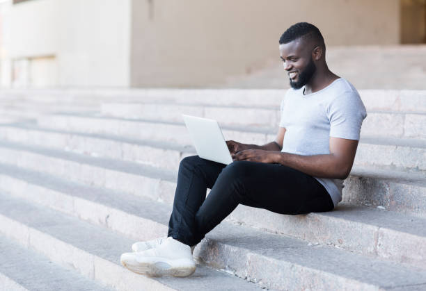 istock African american freelancer working on laptop sitting on stairs 1165260224