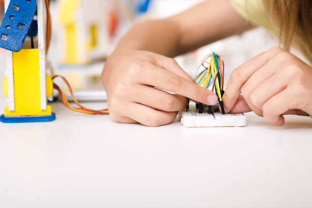 istock Child's hands working with wires and circuits 1165260431