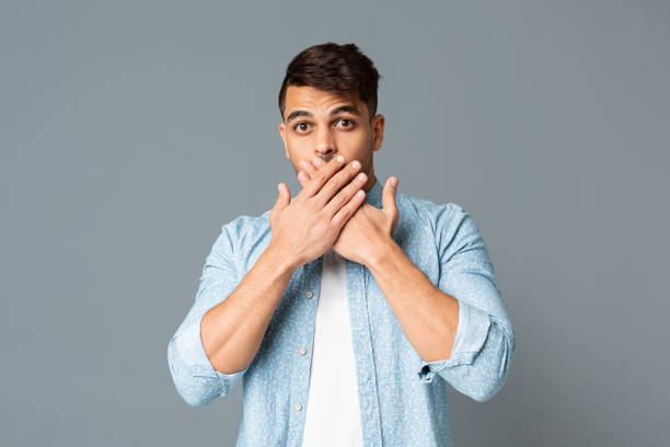 istock Shocked guy covering his mouth with hands on gray background. 1165260442