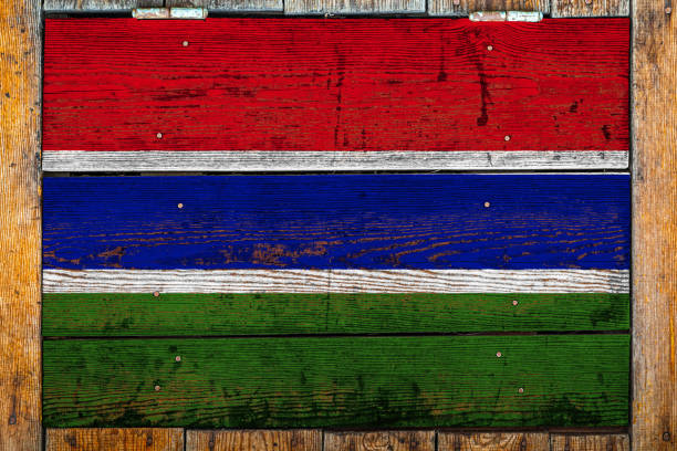 National flag of Gambia on a wooden wall background.The concept of national pride and symbol of the country.Flag painted on a wooden fence with metal nails.