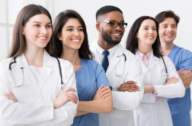 Diverse team of doctors posing in hospital in row Diverse team of doctors posing in hospital, headed by main practitioner medical student photos stock pictures, royalty-free photos & images