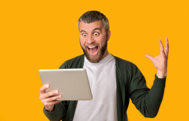 istock Excited bearded man holding tablet and screaming 1165262075