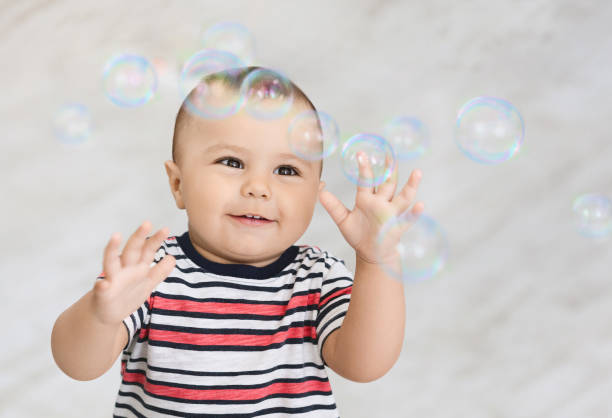 istock Cute small baby boy playing with many soap bubbles 1165263340