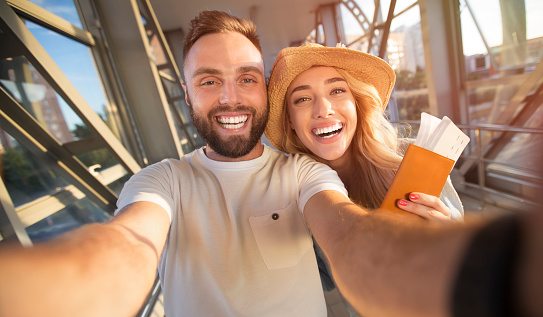Loving couple making selfie at airport terminal before leave for flight