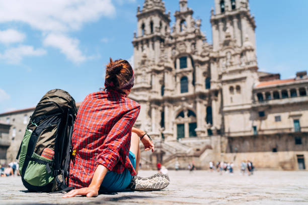 Woman backpacker piligrim siting on the Obradeiro square (plaza) in Santiago de Compostela stock photo