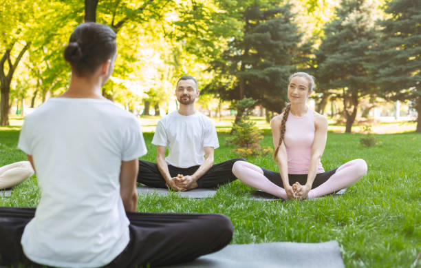 istock Yoga beginners listening to instructor sitting in Lotus pose 1165264733