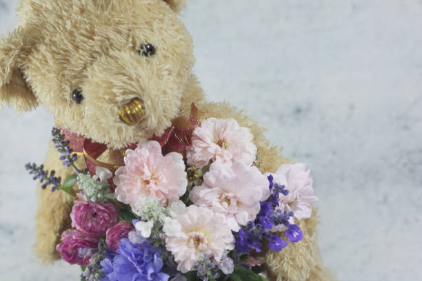 istock Teddy bear foll with flower bouquet. 1165265005