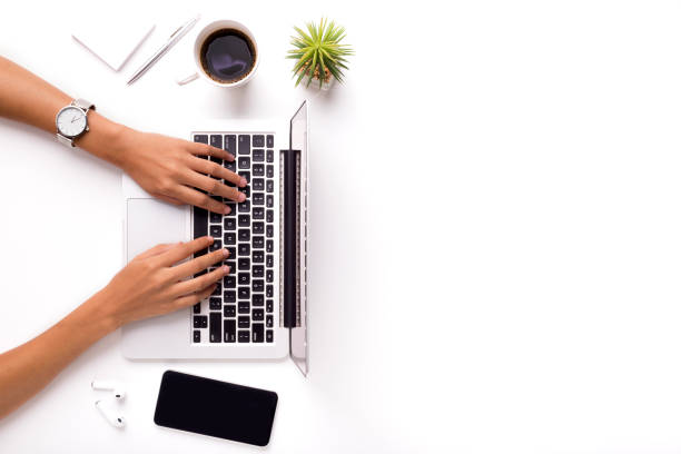 donna che digita su laptop su tavolo da ufficio bianco pulito con pianta - tavolo immagine foto e immagini stock