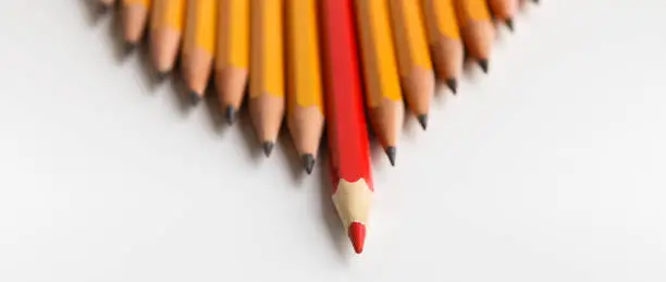 Photo of One red pencil followed by group of similar ones
