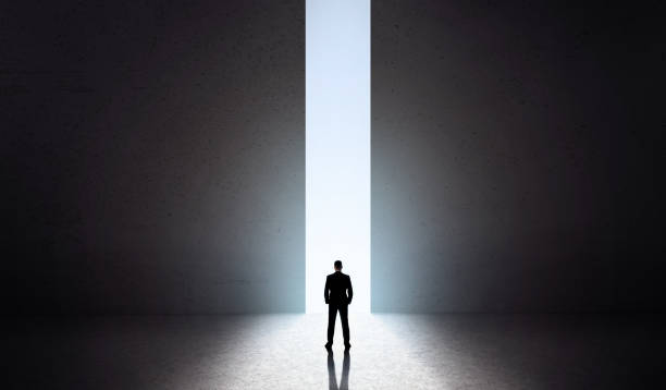 istock Man silhouette in front of opening concrete doors 1165267708