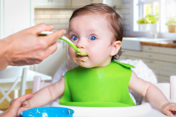 istock Baby girl is surprised about the first time feeding with solid foods 1165268198