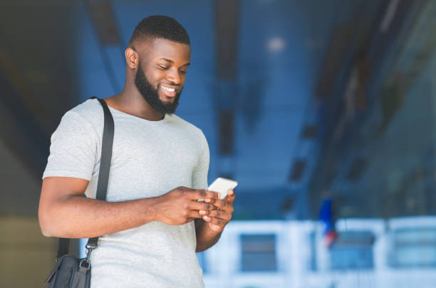 istock Casual african businessman with bag sending textmessage 1165269457