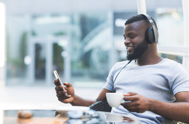 istock Handsome african guy in headphones with cellphone 1165269670