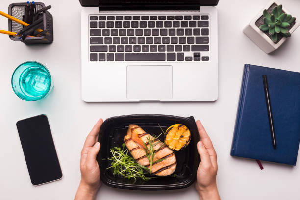 istock Fish in take away black box in woman hands on office table 1165269732