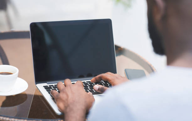 istock African man typing on laptop with black blank screen in cafe 1165270179