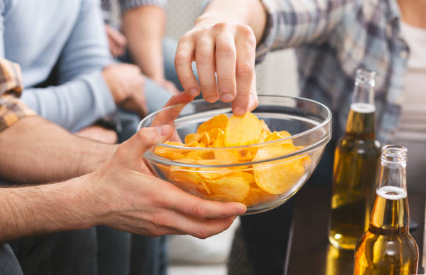 istock Man holding bowl with chips sharing with friends at party 1165270297