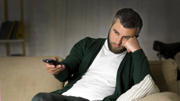 istock Bored man switching channels on TV at home 1165271334