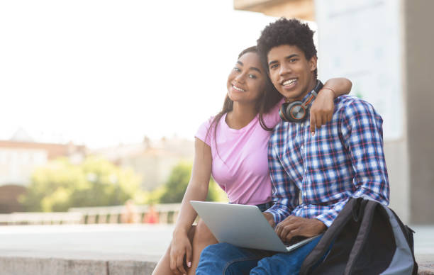 istock Teenage couple using laptop outdoors posing to camera 1165271416