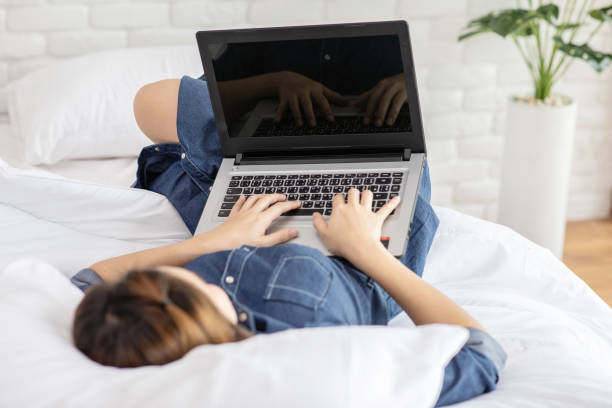 istock Beautiful Attractive Asian young woman lying on bed and using computer laptop for using social media and shopping online relax in cozy bedroom in holiday,Lifestyle in bedroom Concept 1165275680