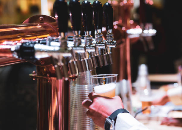 istock Bartender pouring draft beer in the bar, Barman hand at beer tap pouring draught lager beer serving in a restaurant or pub 1165275821