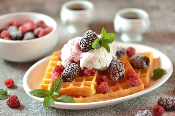 Belgian waffles with ice cream, mint and frozen raspberries and blackberries. Tasty breakfast. stock photo