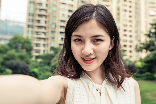 Asian woman taking a selfie with her mobile phone.