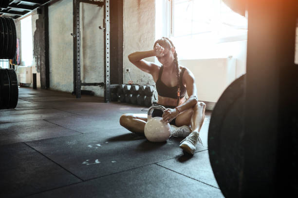 Young fit woman exercise with kettle ball getting tired Young fit woman exercise with kettle ball cross training photos stock pictures, royalty-free photos & images