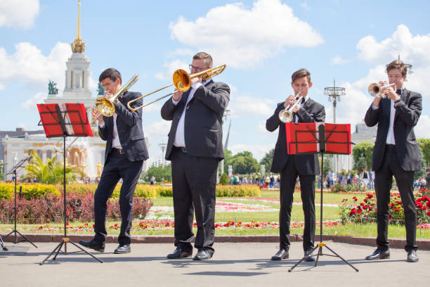 new life brass band, musiciens d'instruments de musique à vent, orchestre effectue un gros plan musical, quatre musiciens hommes jouent des trompettes et des trombones le jour ensoleillé d'été dans le parc vdnkh - vdnh photos et images de collection