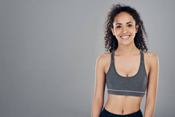 Cropped studio portrait of an attractive young sportswoman smiling while standing against a grey background