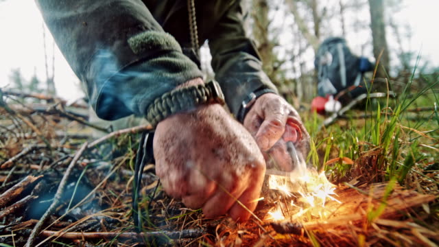 SLO MO LD Hands of a man starting a fire using a Ferrocerium rod and a knife