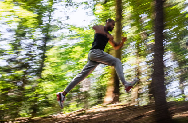 istock Young Man Running Through The Woods, Blurred Motion 1165284517