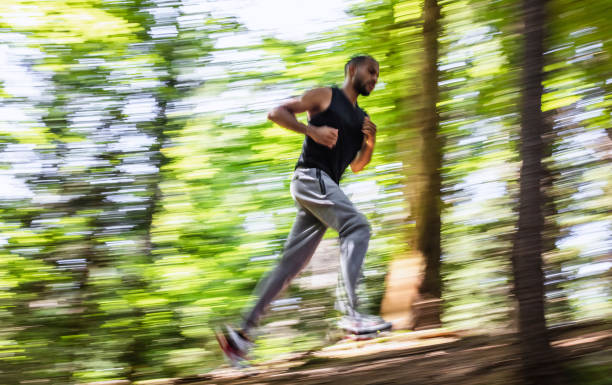 istock Young Man Running Through The Woods, Blurred Motion 1165285081