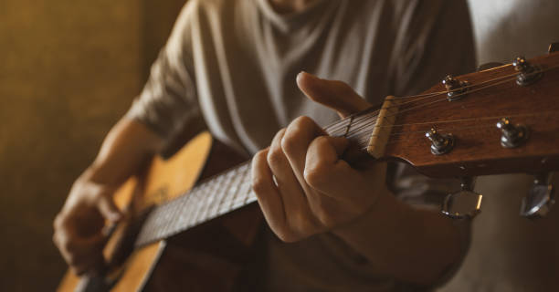 istock Asian guy playing acoustic guitar close up. 1165285162