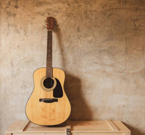 istock Acoustic guitar against concrete wall. 1165285275