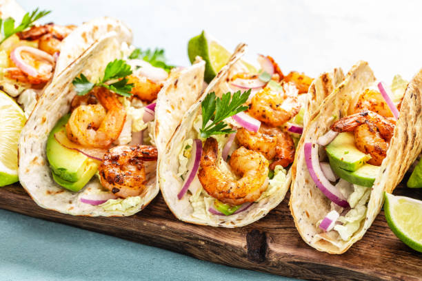 tacos de camarón. fajitas de marisco con repollo, cebolla, perejil en tortillas servidas en tabla de cortar de madera - grilled shrimp fotos fotografías e imágenes de stock