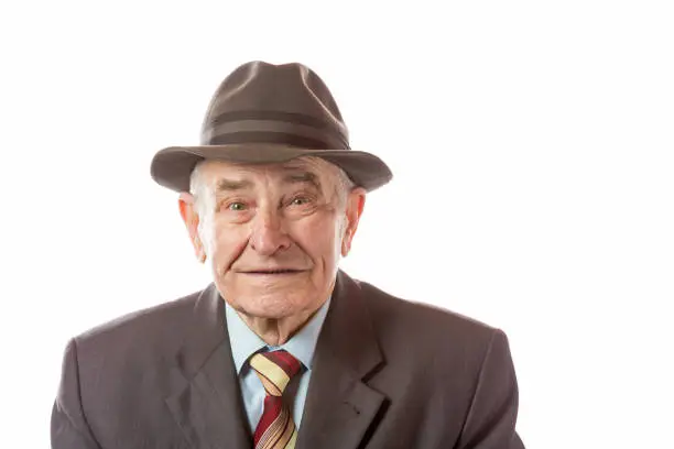 Portrait of 90 year old senior man in retro hat looking at camera isolated on white background