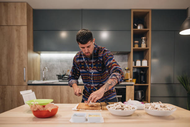 Handsome man dancing and listening to music while preparing food