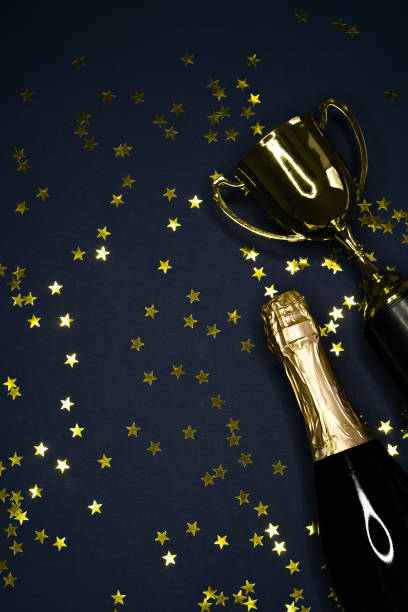 istock gold winning cup and champagne bottle  on dark blue background , success concept 1165291354