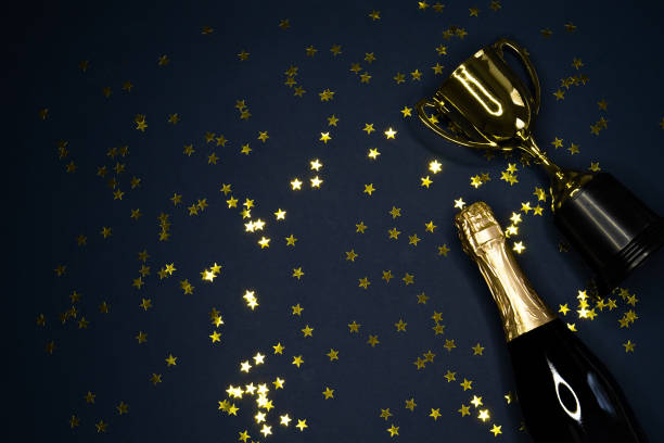 istock gold winning cup and champagne bottle  on dark blue background , success concept 1165291484