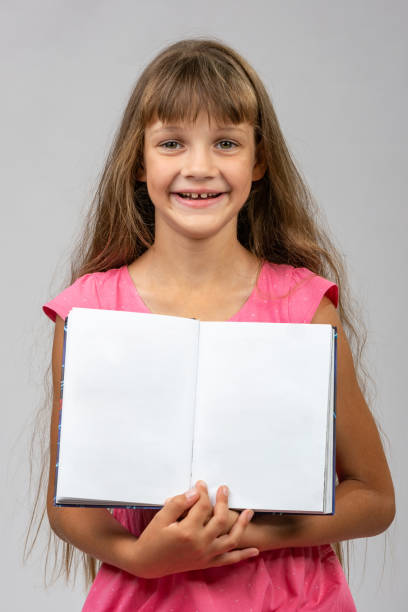 istock The girl cheerfully shows the opened empty book in her hands 1165294313
