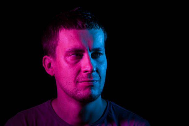 Portrait of a man whose head is turned to the side highlighted in pink and blue