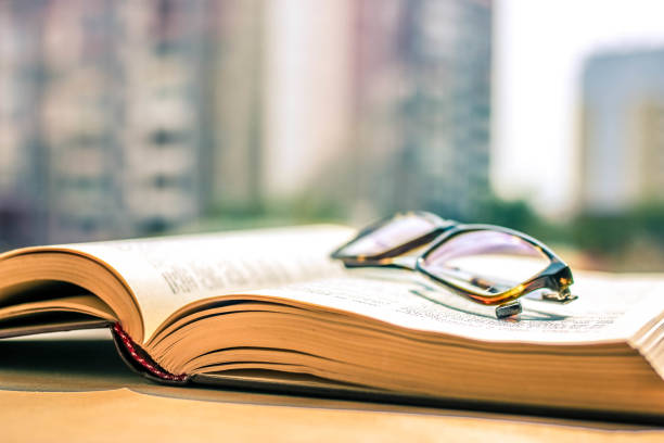 istock Eye glasses on the big open book and beautiful blurred background. Educational concept. 1165294843