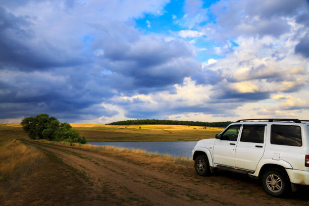 Saratov, Russia - 06/28/2019: Travel, tourism by car SUV. White UAZ Patriot in the evening on the nature on the road against the background of the field, forest and dramatic sky with clouds before a thunderstorm Saratov, Russia - 06/28/2019: Travel, tourism by car SUV. White UAZ Patriot in the evening on the nature on the road against the background of the field, forest and dramatic sky with clouds before a thunderstorm uaz 4x4 land vehicle woods stock pictures, royalty-free photos & images