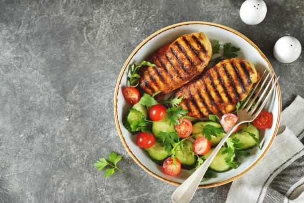 grilled healthy chicken breast with a salad of cherry tomatoes, cucumbers, arugula and parsley. top view. - chicken breast chicken grilled chicken protein imagens e fotografias de stock