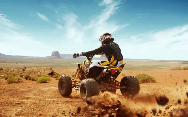 Quad bike in dust cloud, sand quarry on background. ATV Rider in the action.