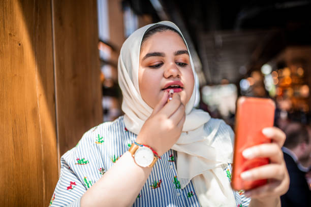 istock Muslim girl putting on a red lipstick 1165300051