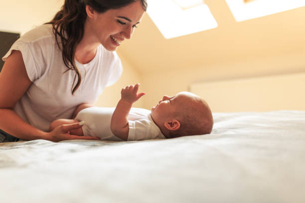 istock Mother playing with her baby on the bed . 1165300069